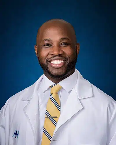 Professional headshot of Dr. Alieu Kanu, DPM, AACFAS, wearing a white coat and striped tie, smiling.