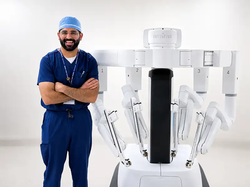 General surgeon Dr. Shyamal Pansuriya smiling alongside the new da Vinci 5 robotic surgical system at Artesia General Hospital.